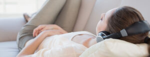 girl resting on couch with headphones on